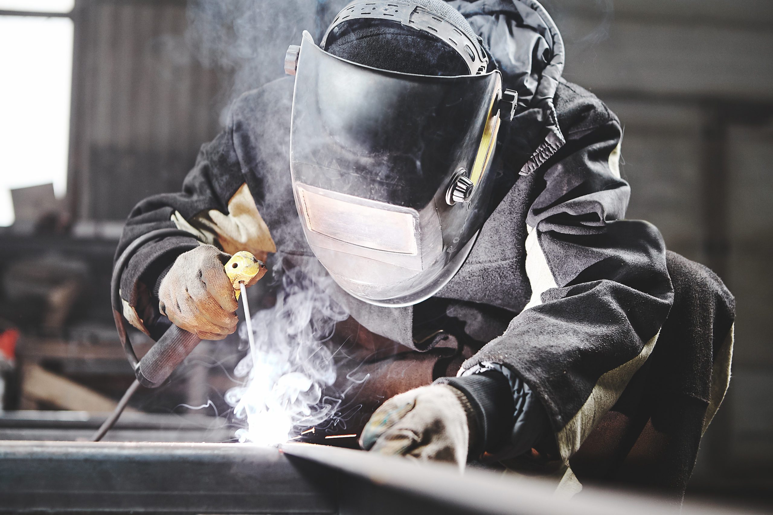 Welder working with welding on metal frames in an industrial plant. Industrial work.